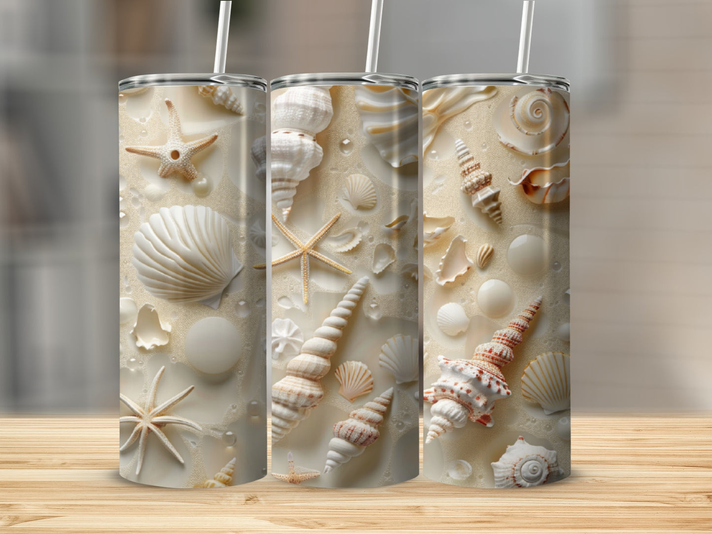 Three tumblers with seashell and starfish patterns on a sandy background.