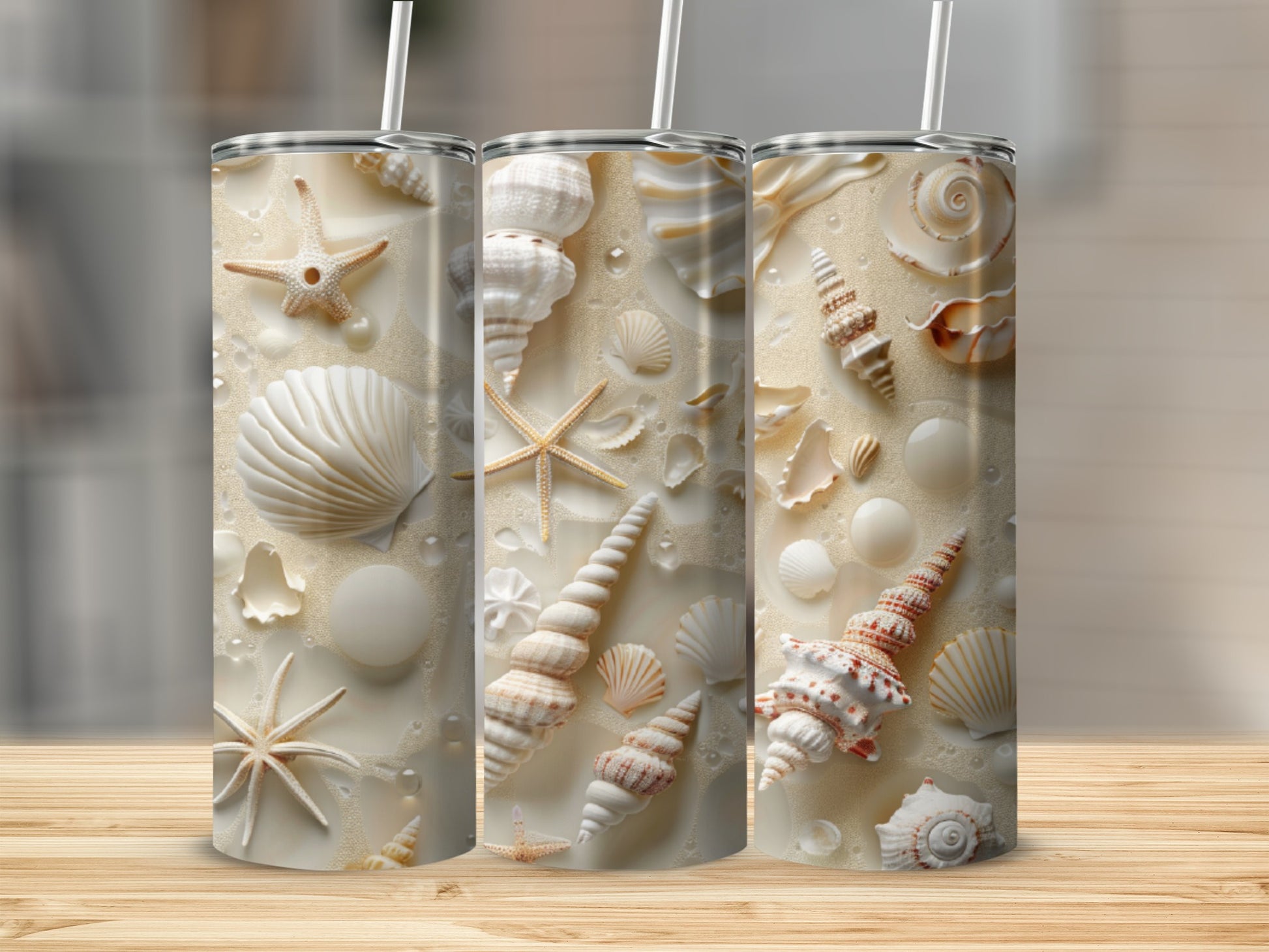 Three tumblers with seashell and starfish patterns on a sandy background.