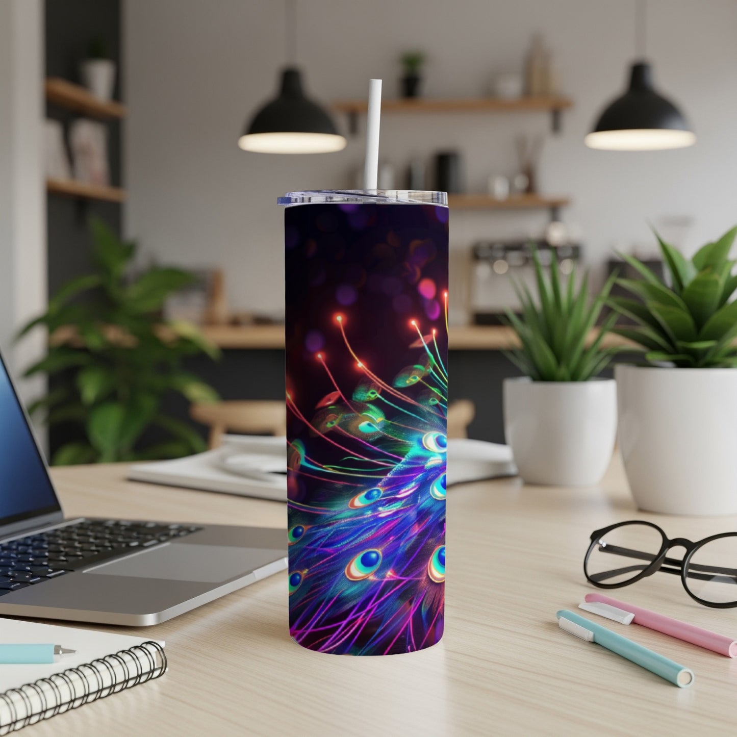 Tall tumbler with a vibrant peacock feather design on a desk.
