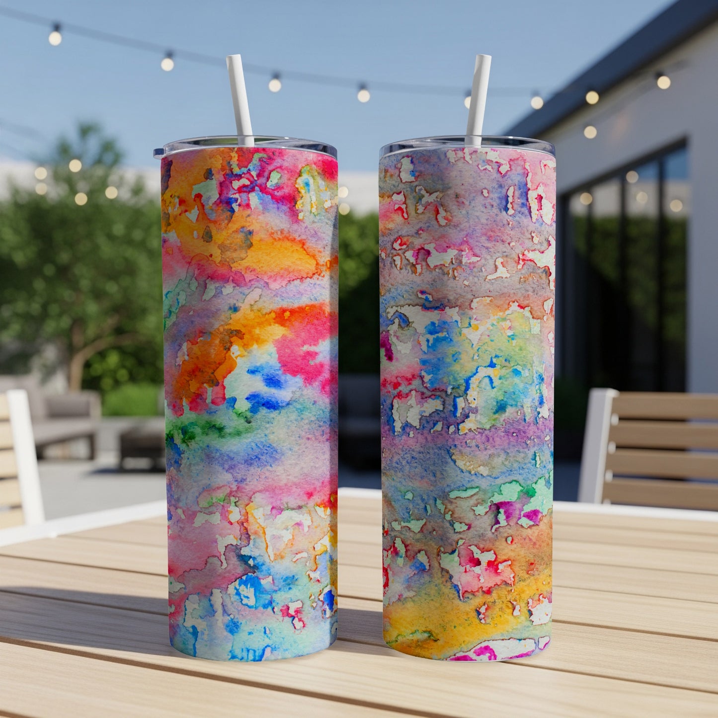 Two tumblers with a colorful watercolor abstract pattern on a table.