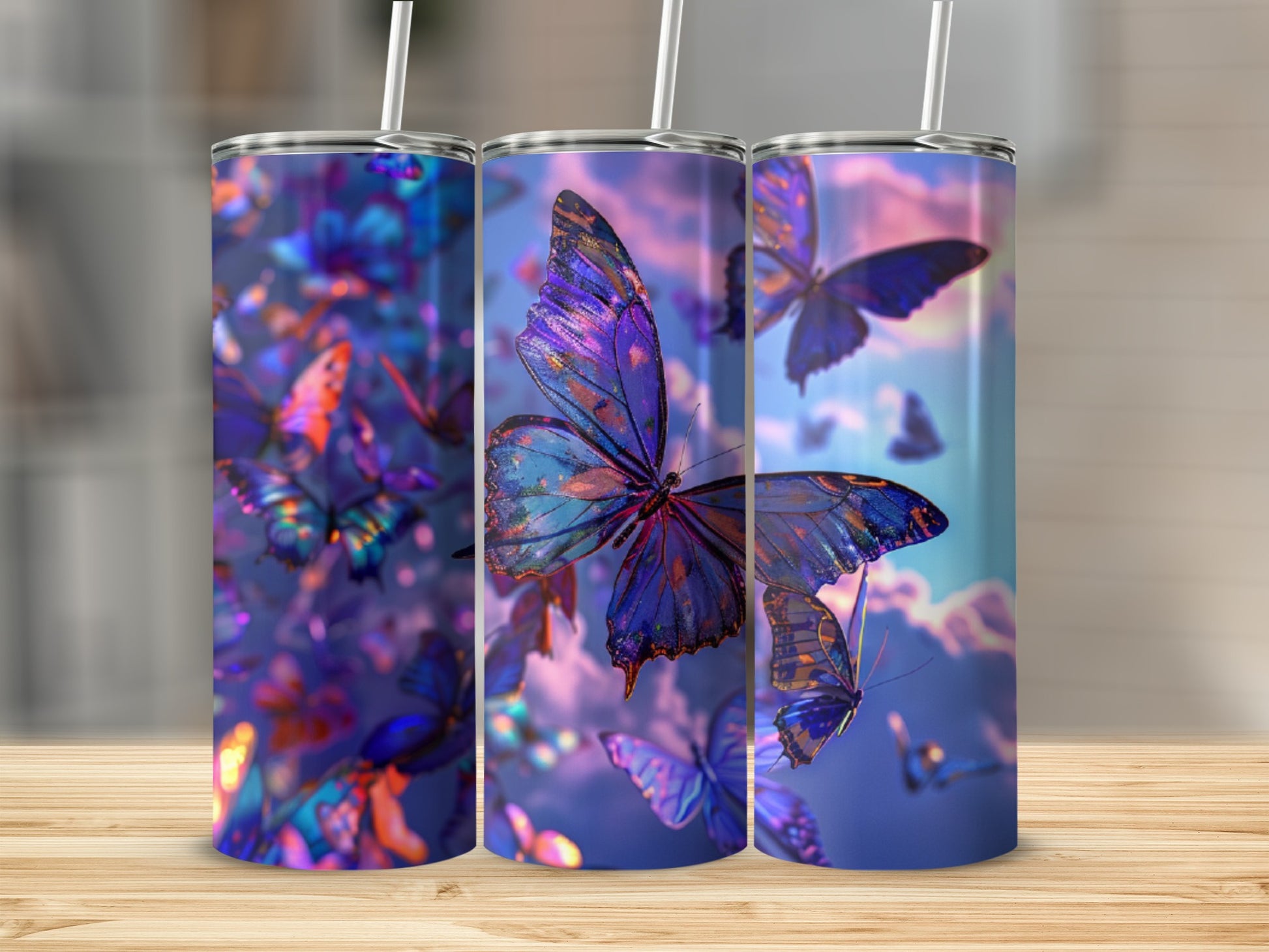 Three tumblers featuring iridescent butterflies and clouds against a purple sky.