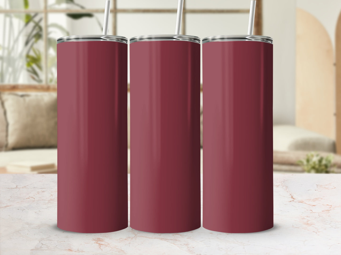 Three burgundy tumblers with straws on a marble countertop.