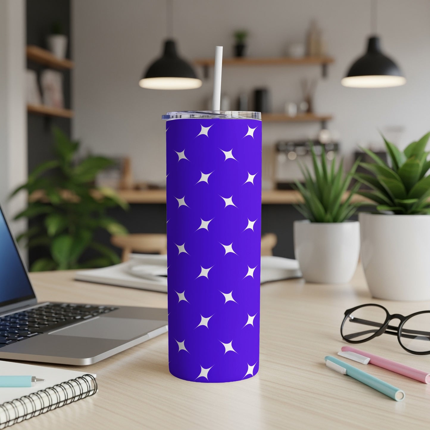 Purple tumbler with white stars and a white straw on a wooden desk.