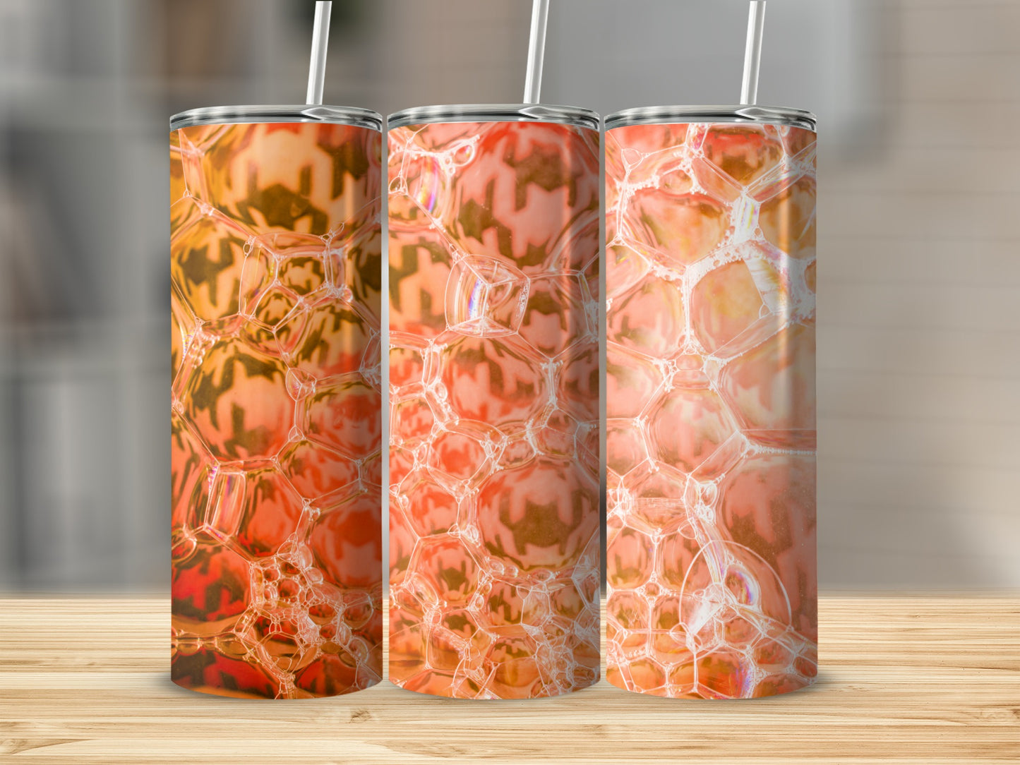 Three tumblers with orange bubble pattern on a wooden surface.