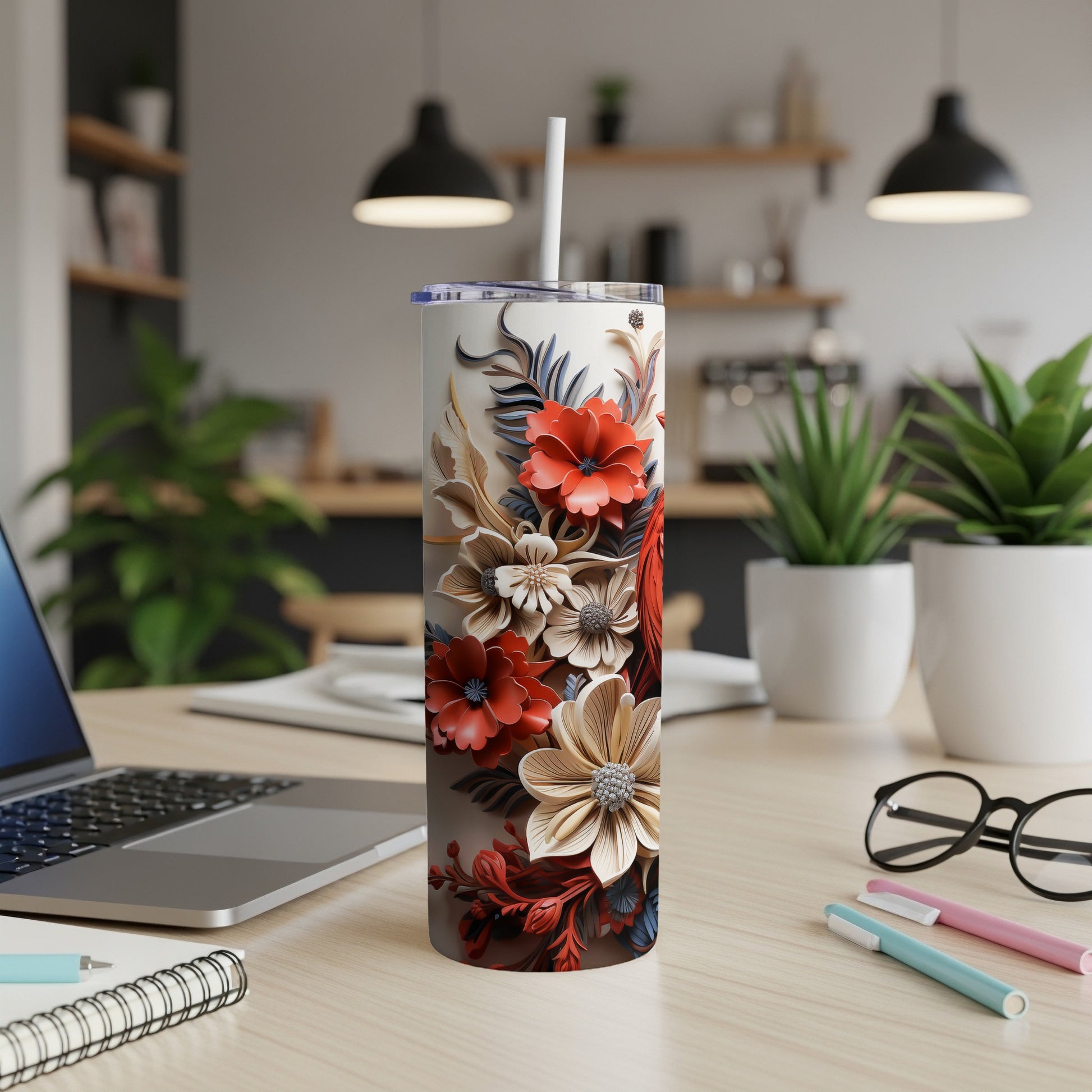 Floral tumbler with straw on a desk with laptop and plants.