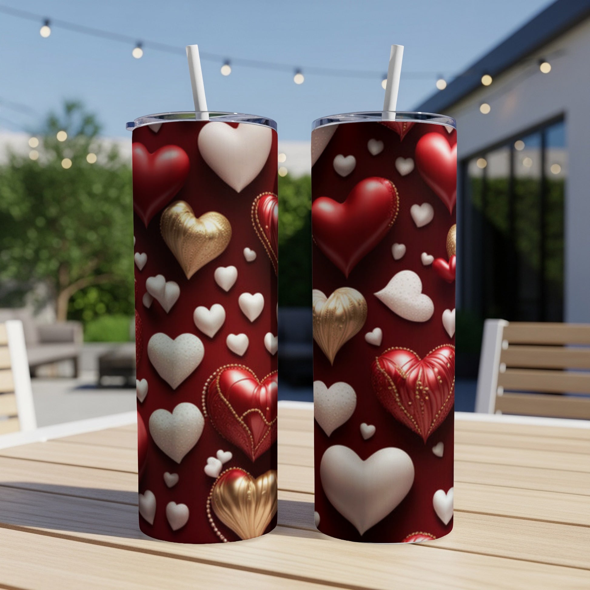 Two heart-patterned tumblers with straws on a wooden table.