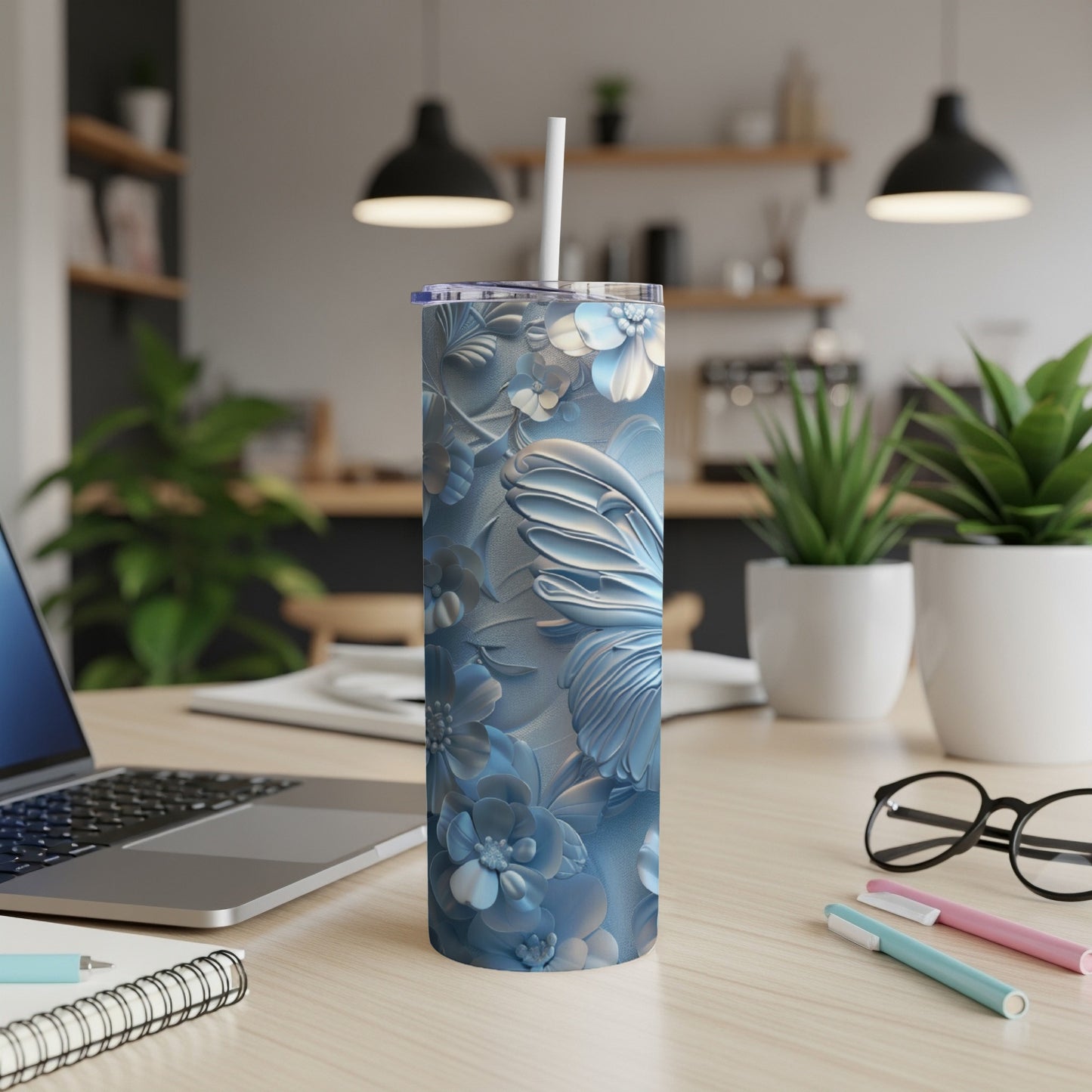 Blue butterfly and floral embossed stainless steel tumbler with straw on desk.