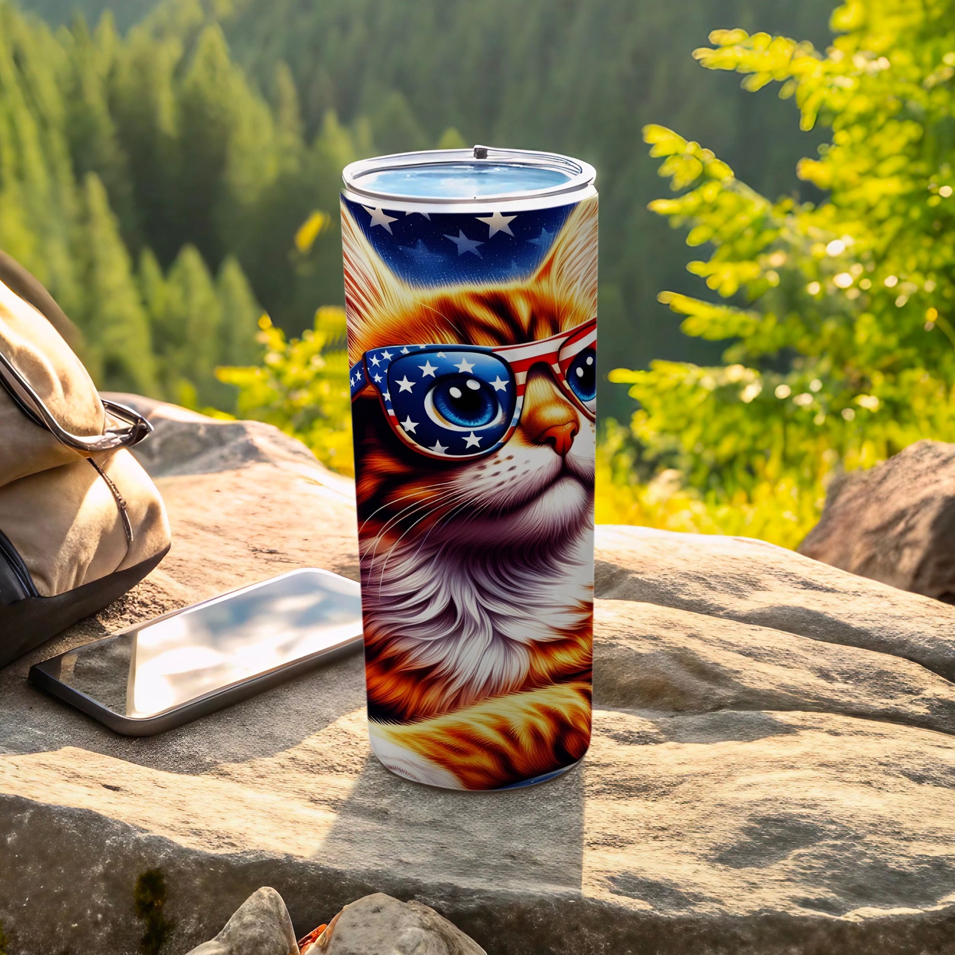 Cat wearing American flag sunglasses, on a rocky surface with phone and backpack.