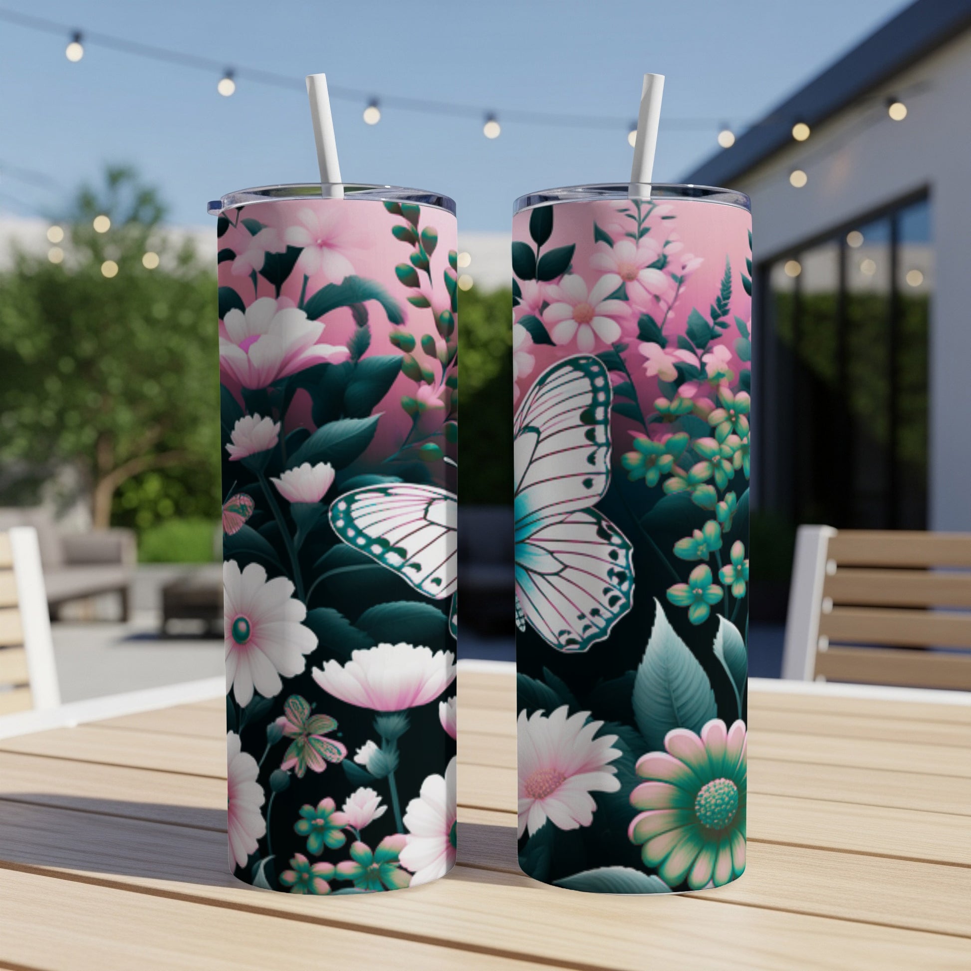 Two floral tumblers with butterflies and straws on a table.