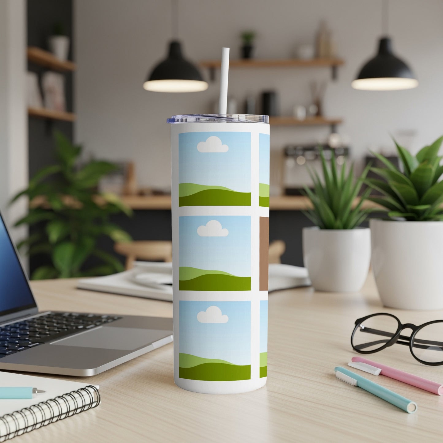 White tumbler with grid of landscape images and a straw in a desk setting.