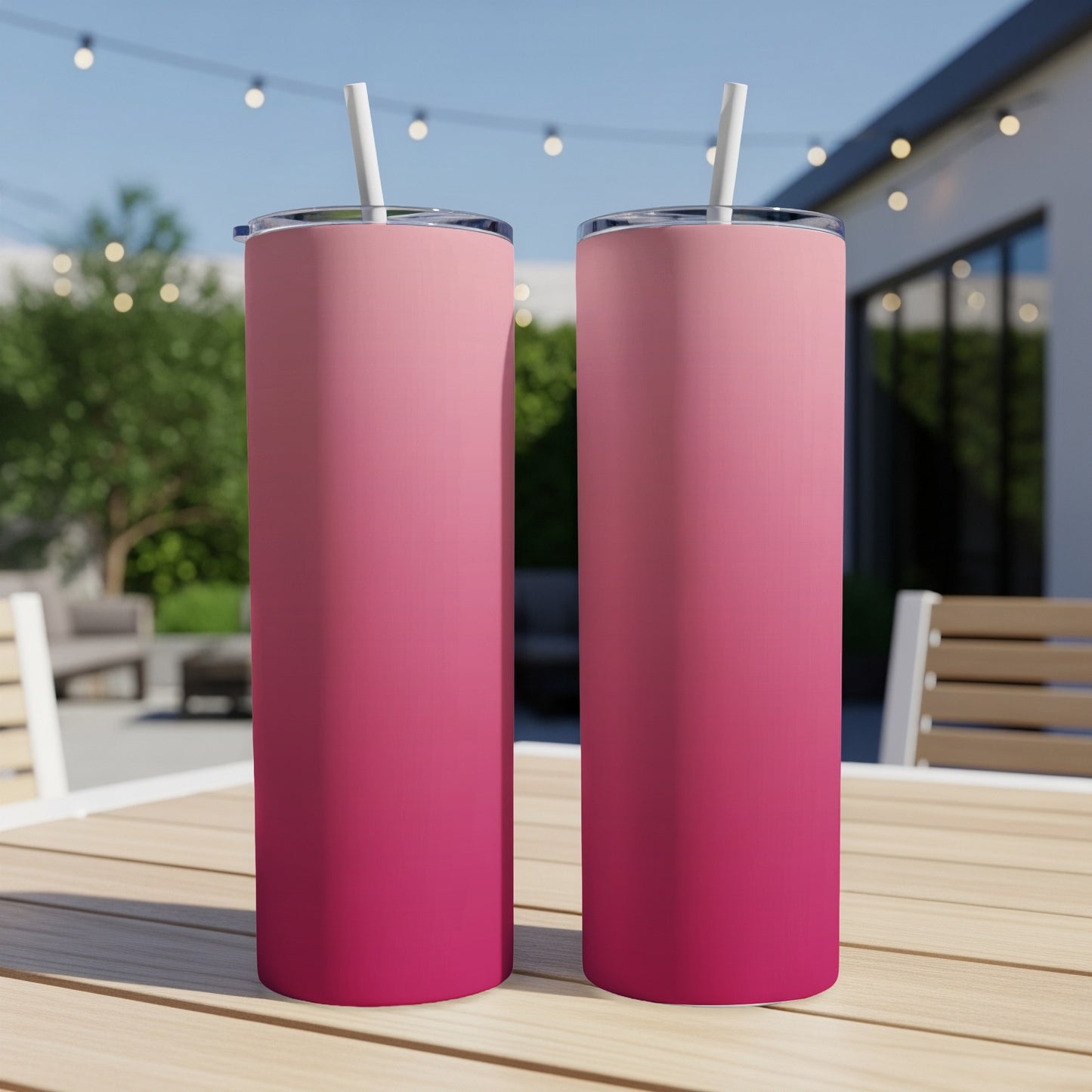 Two pink gradient tumblers with straws on a wooden table.