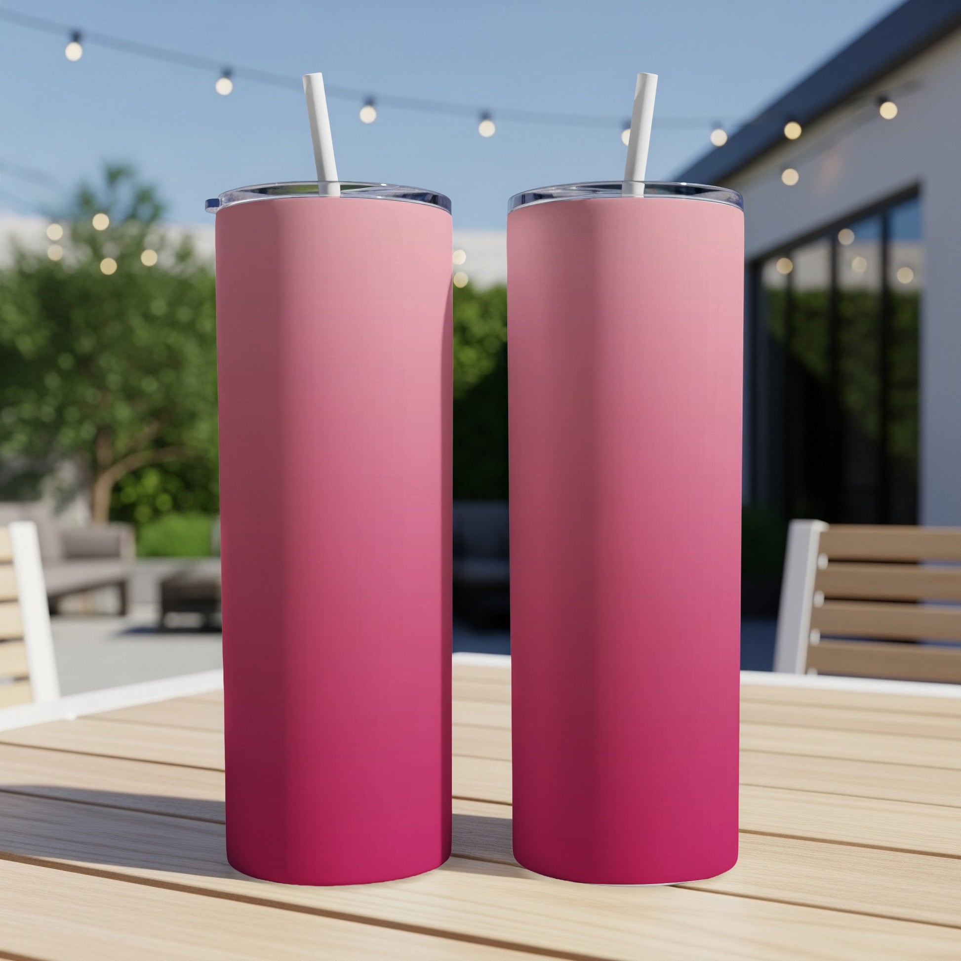 Two pink gradient tumblers with straws on a wooden table.