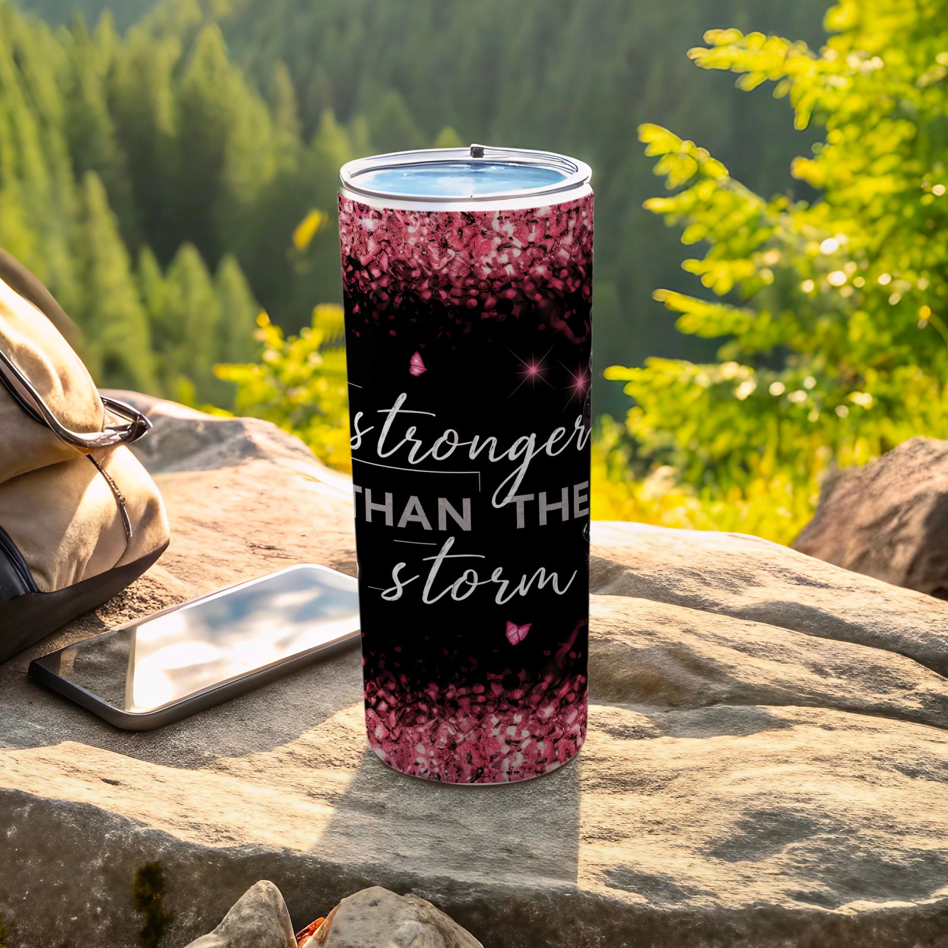 Black tumbler with pink glitter and "stronger than the storm" text.