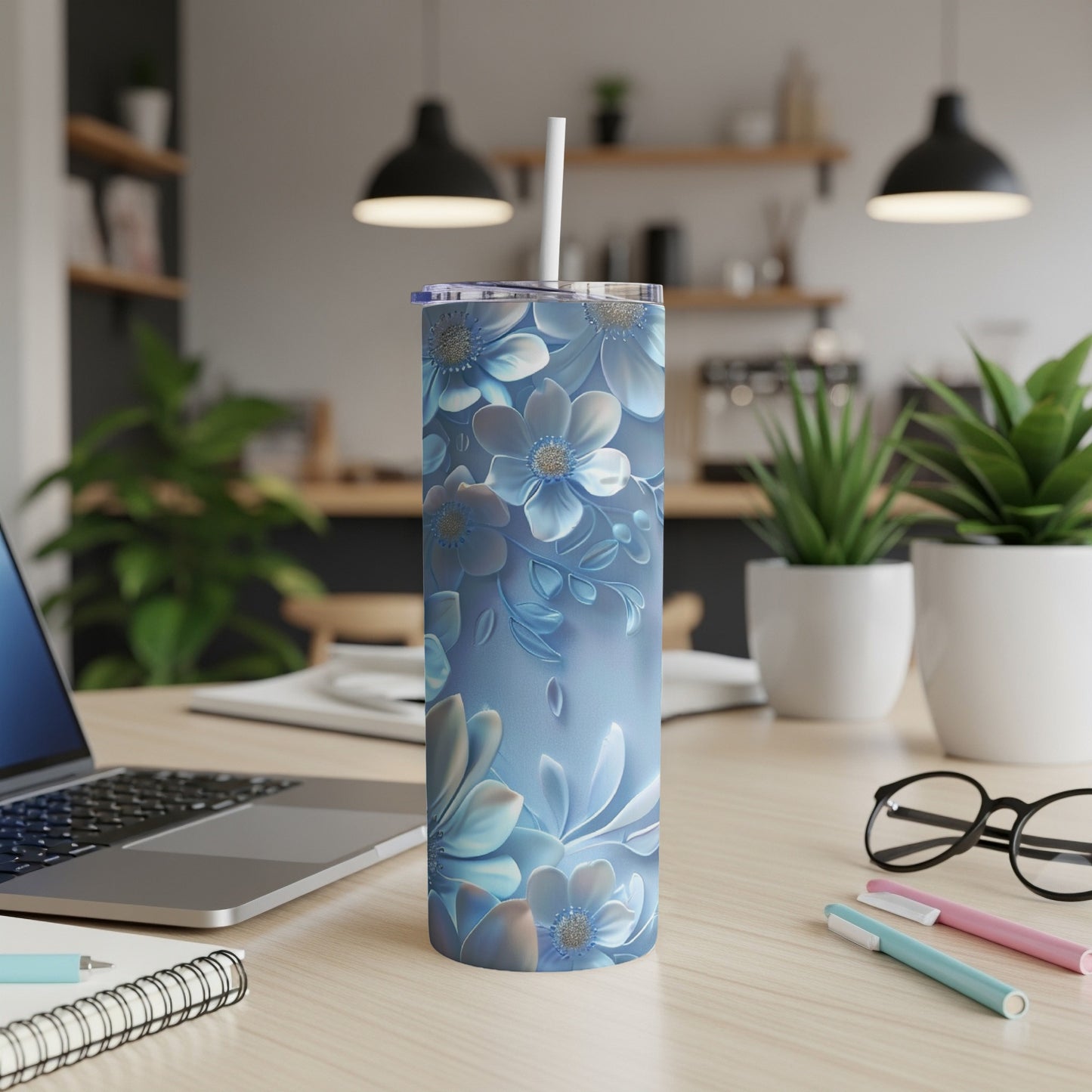 Blue floral tumbler with straw on a desk next to a laptop.