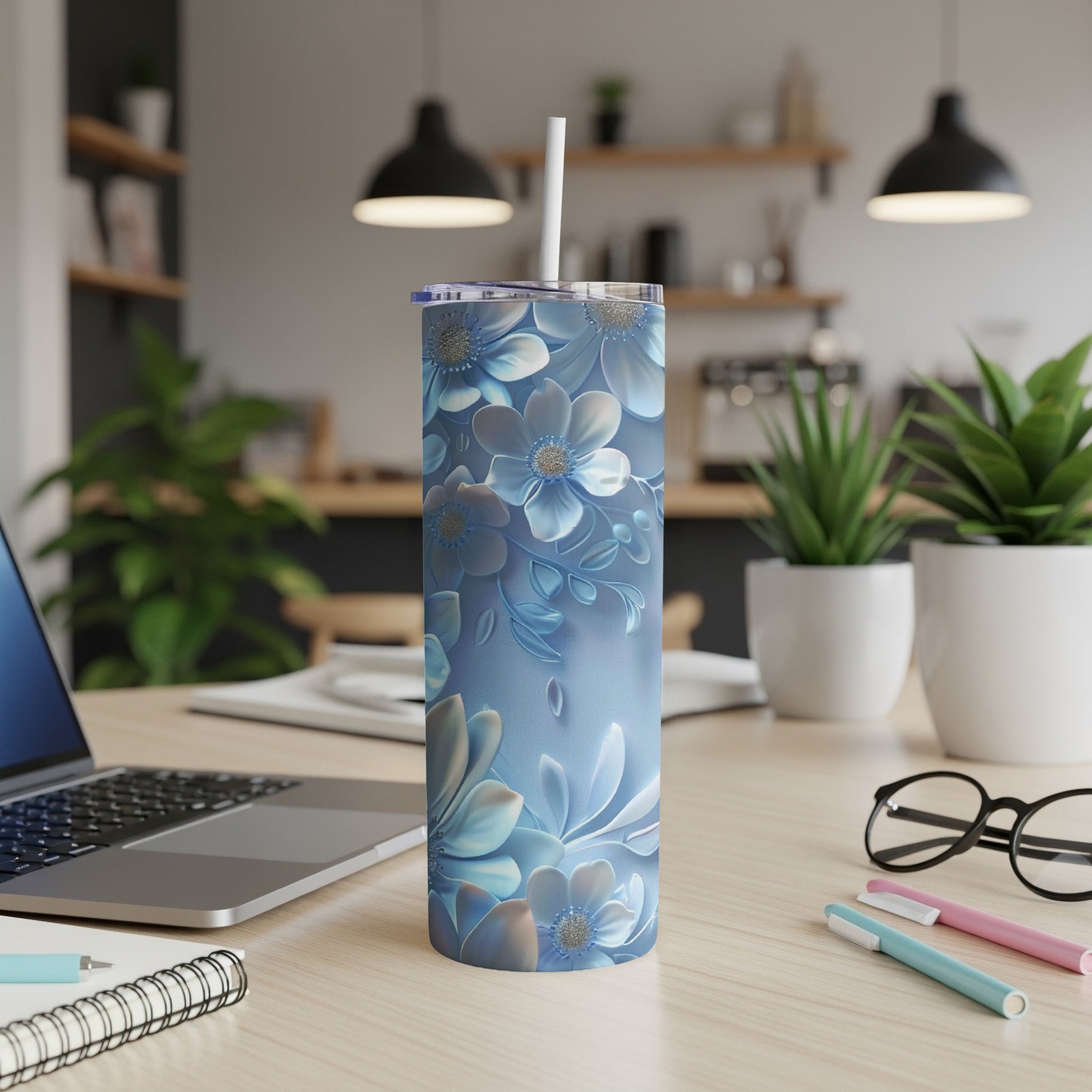 Blue floral tumbler with straw on a desk next to a laptop.