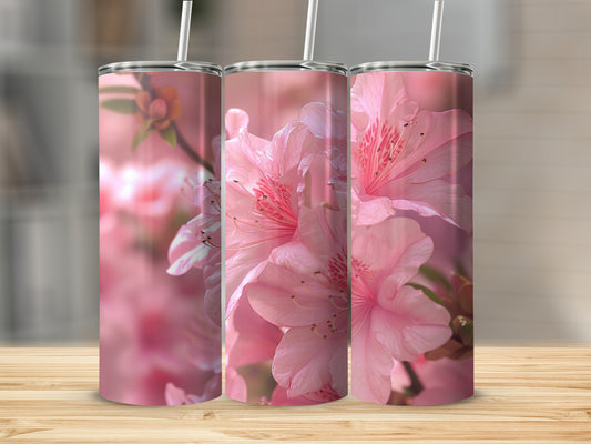 Three pink azalea flowers on a tumbler, with soft background blur.