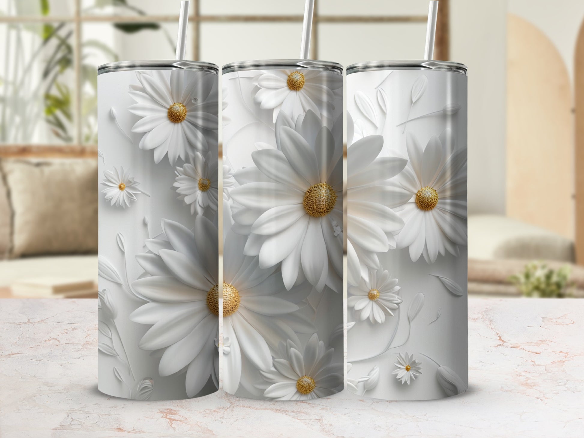Three white daisy floral tumblers with straws displayed on a marble surface.