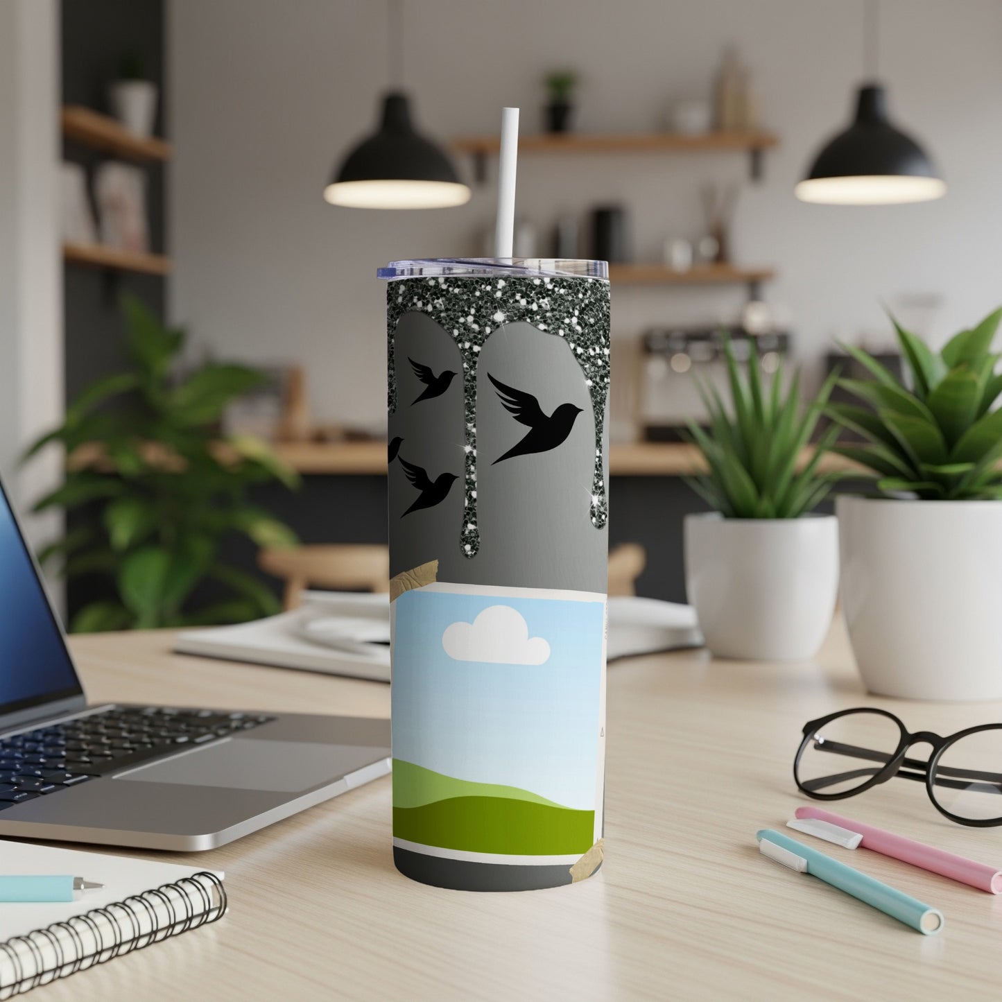 Glittery black bird design on a tall tumbler with a landscape scene below.