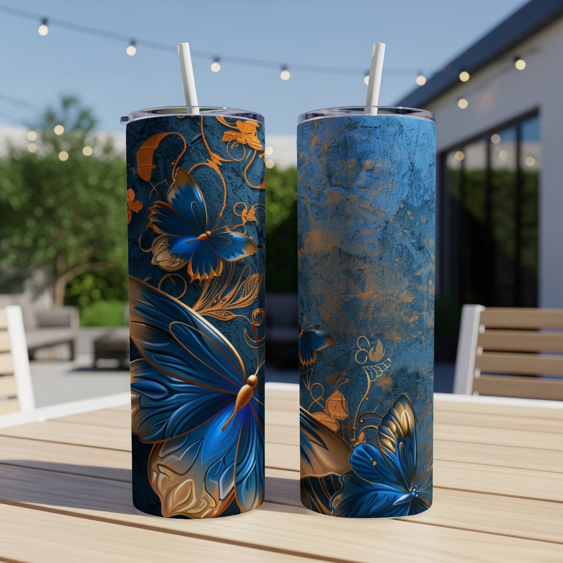 Two blue and gold butterfly tumblers on a wooden table with a backyard scene.