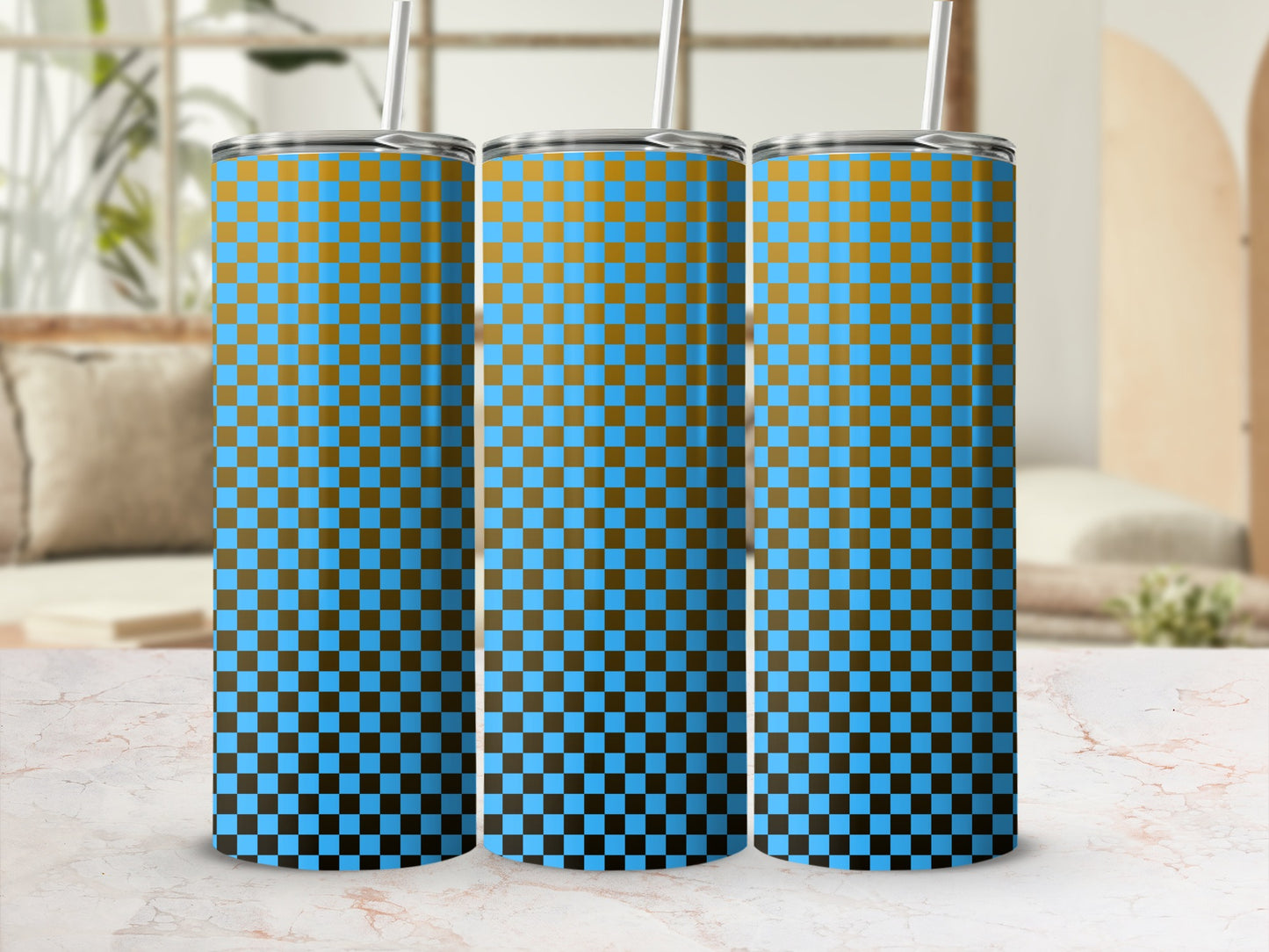 Three blue and gold checkered tumblers with straws on a marble surface.