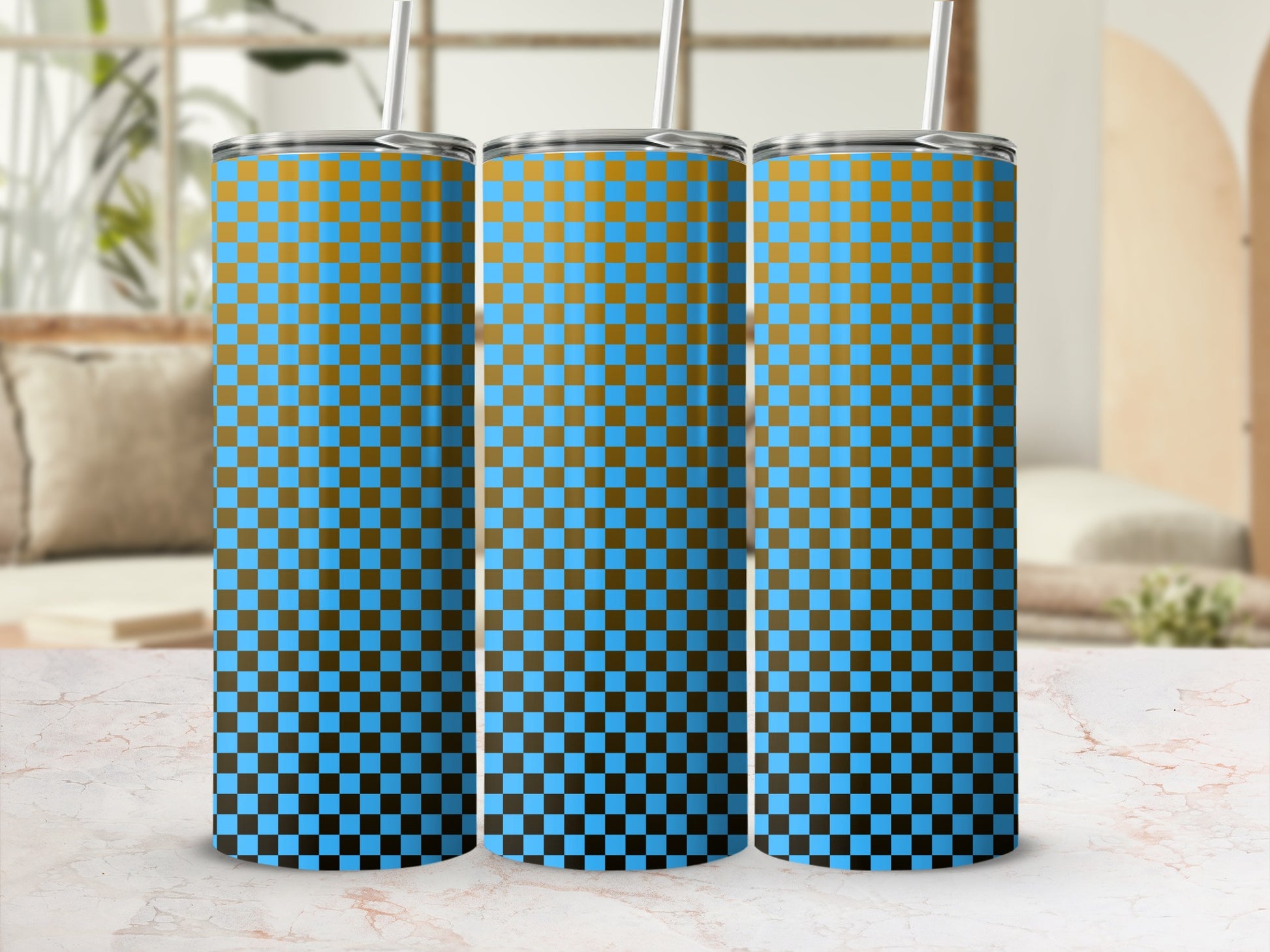 Three blue and gold checkered tumblers with straws on a marble surface.