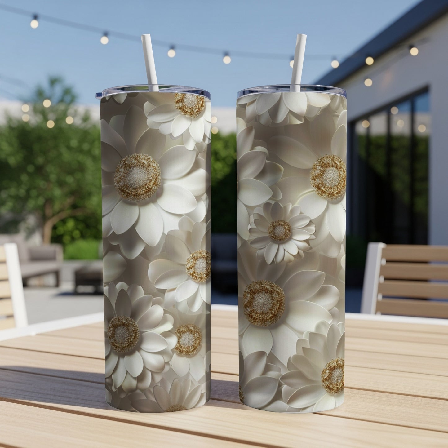 Two white floral print tumblers with straws on a wooden table.