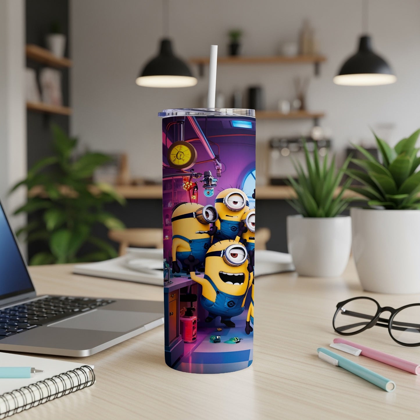 Minions on a tumbler with a straw, sitting on a desk with a laptop.