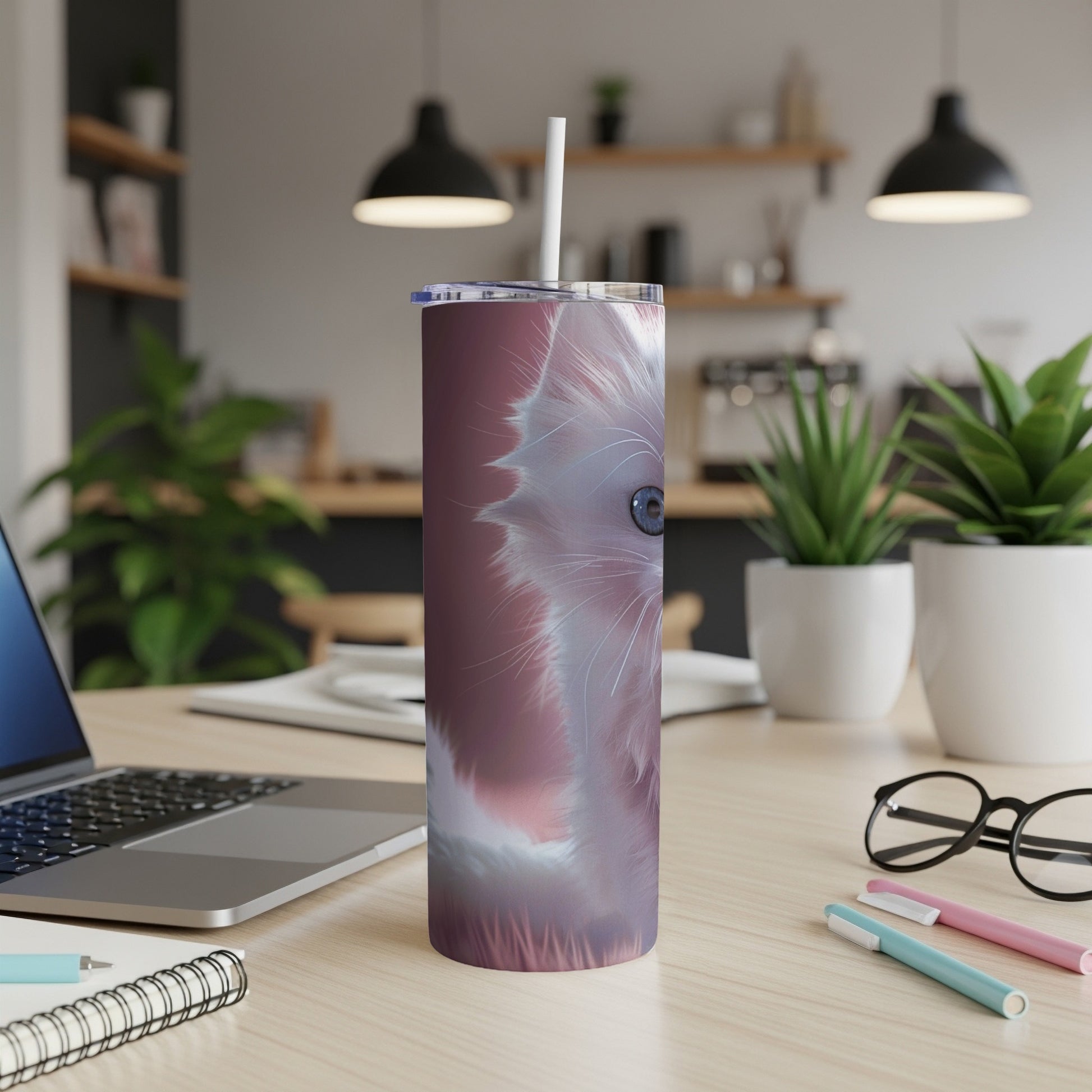White cat face design on a tall, pink tumbler with a straw.
