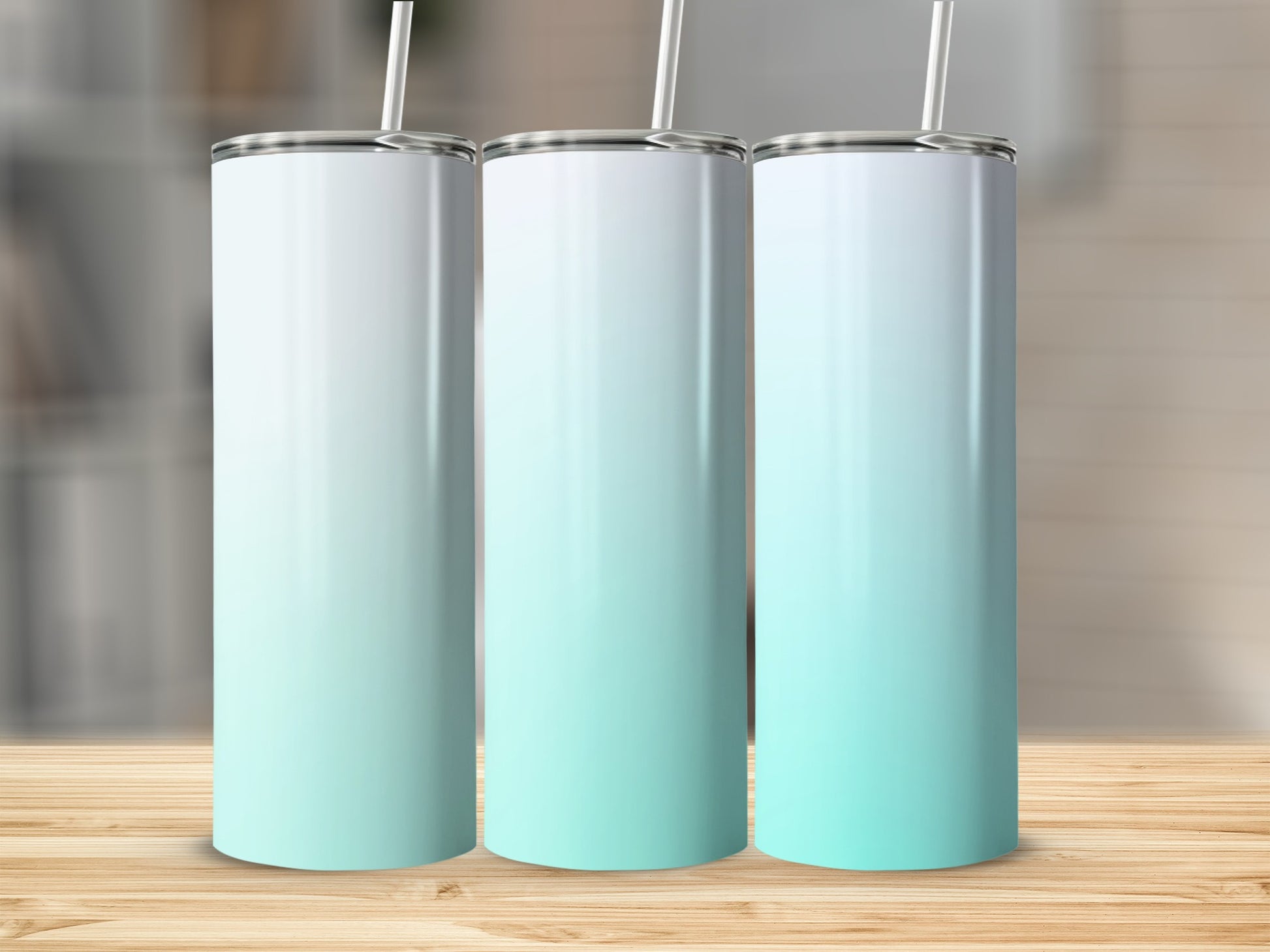 Three tall, ombre gradient tumblers with straws on a wooden surface.