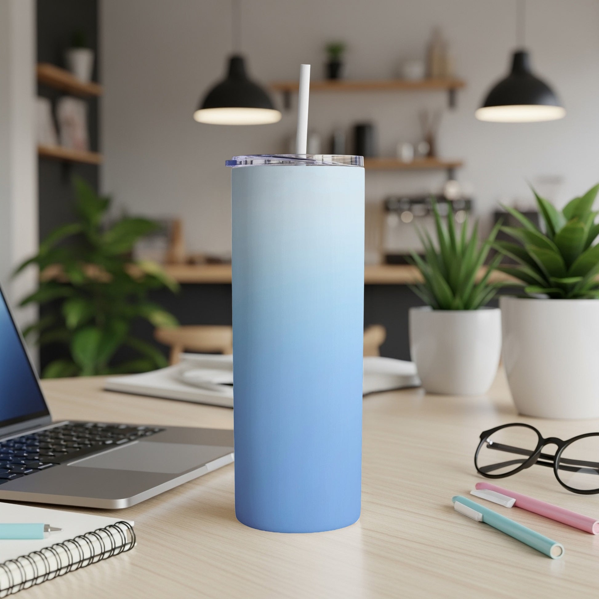 Blue gradient skinny tumbler with straw on a desk.