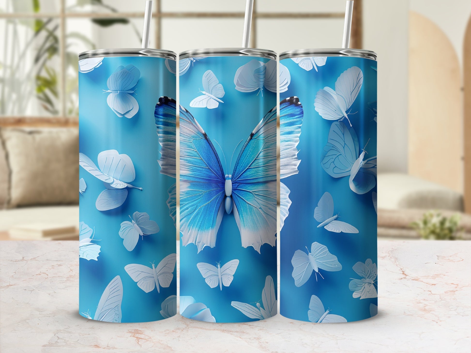 Three blue tumblers with butterfly designs, featuring a large blue butterfly.
