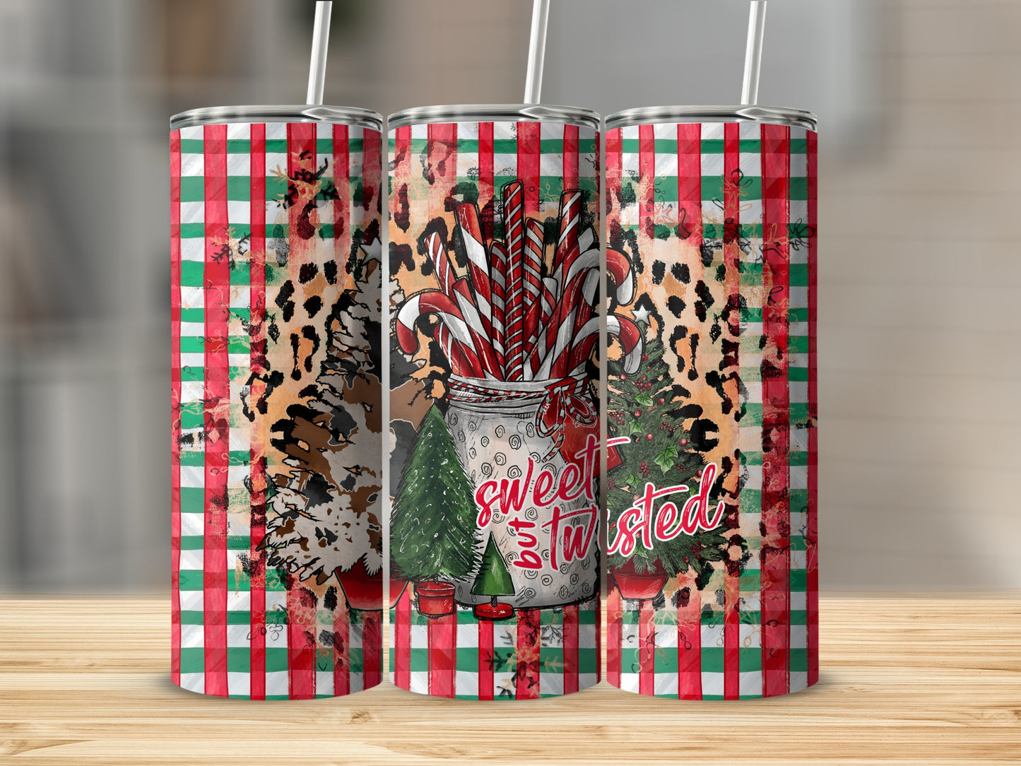 Three tumblers with candy canes, trees, and leopard print on plaid.