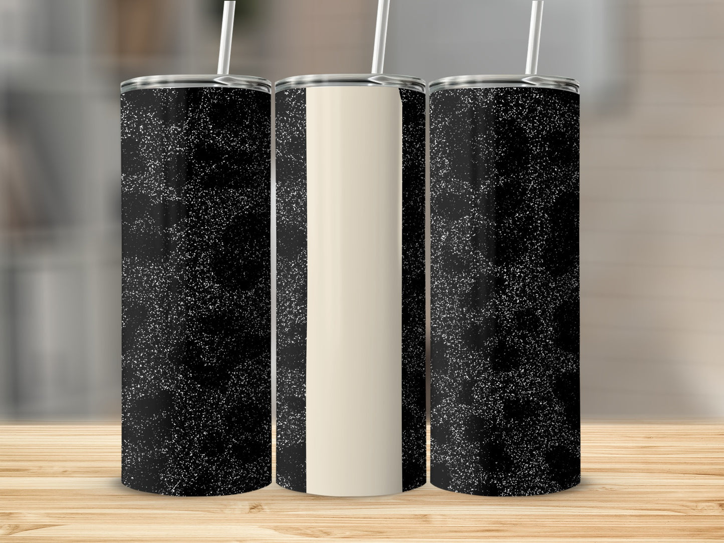 Three tumblers with black glitter and cream stripe designs on a wooden surface.