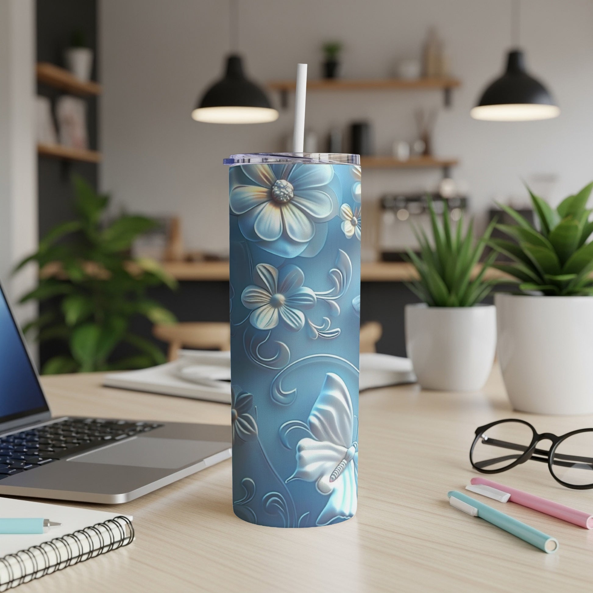 Blue tumbler with floral and butterfly pattern on desk.