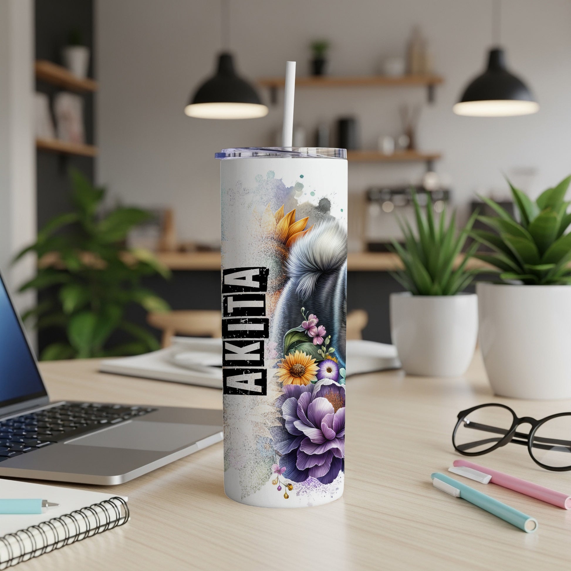 Akita tumbler with floral and dog face design on a desk.
