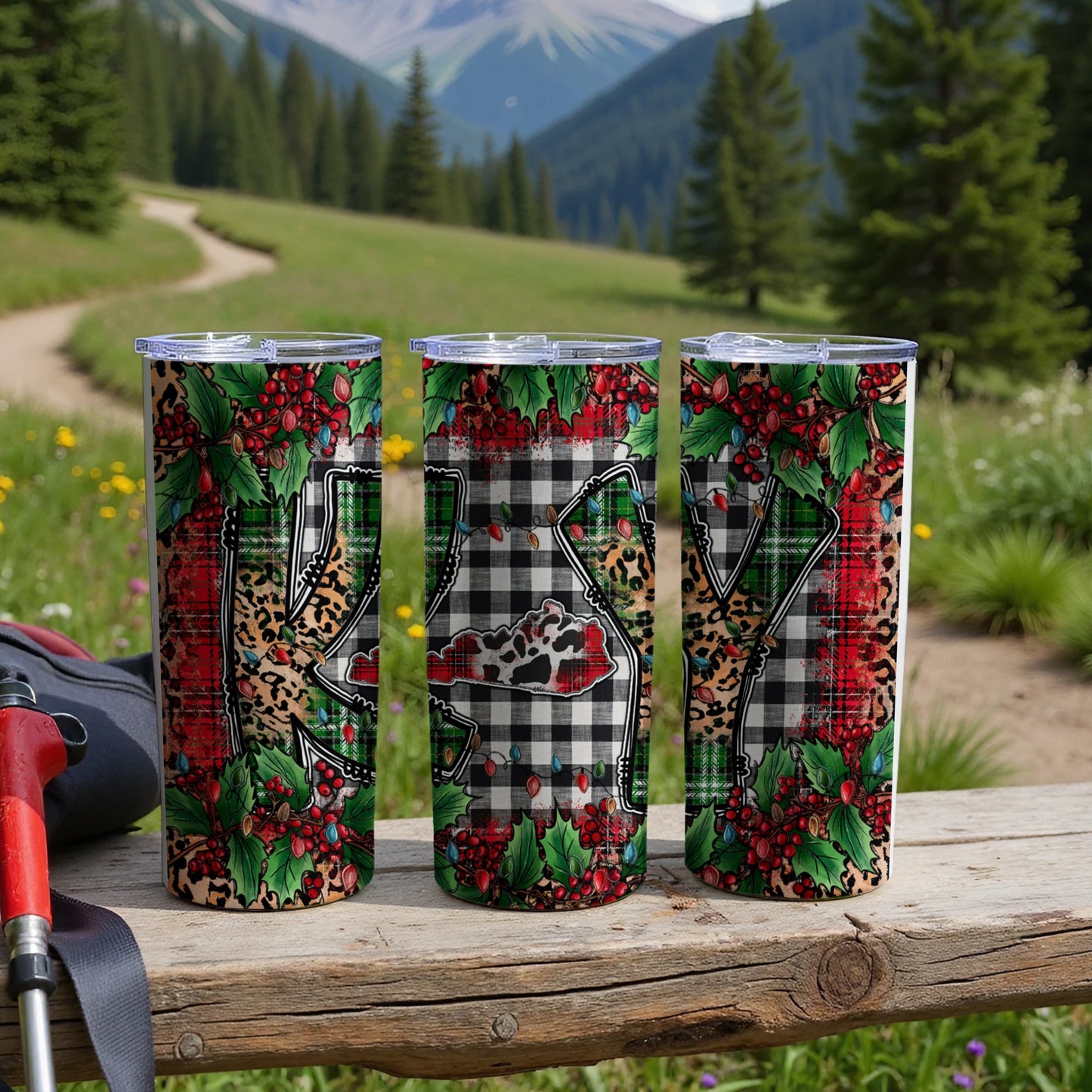 Three Kentucky-shaped tumblers with plaid, holly, and berry pattern outdoors.