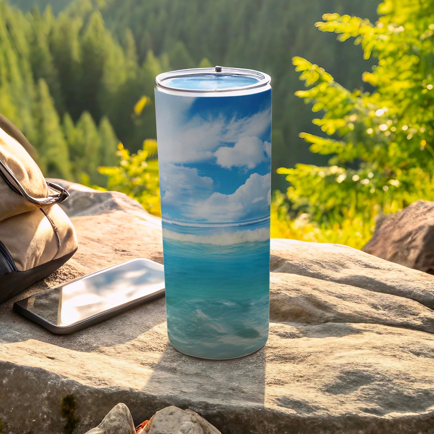 Ocean waves and sky design on a tall tumbler, with phone and backpack nearby.