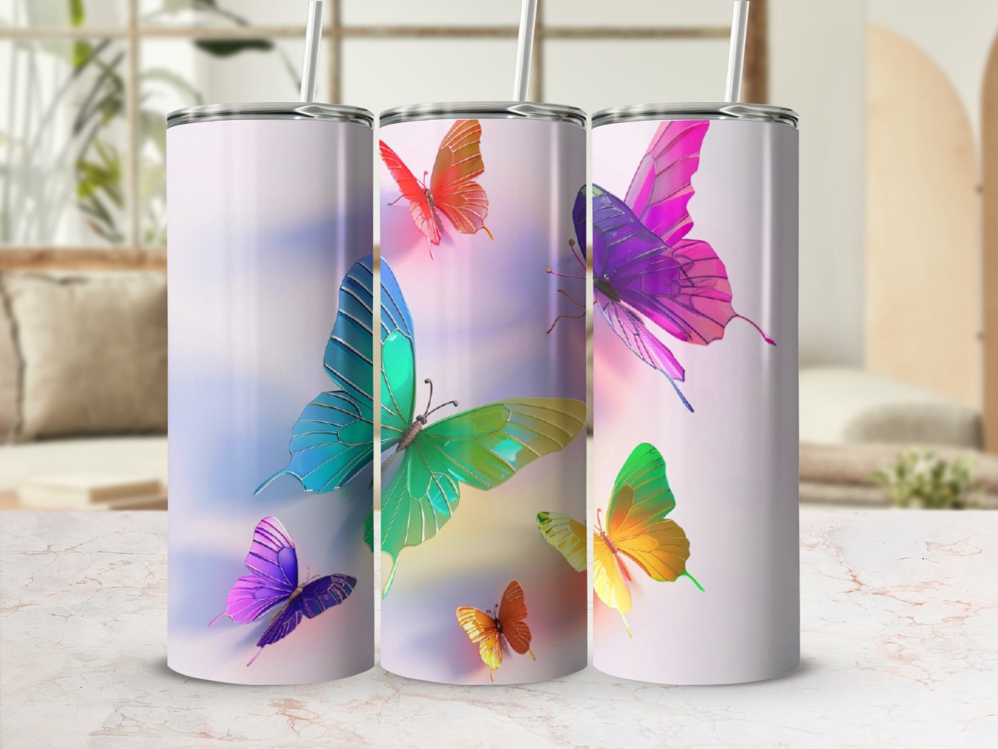Three tumblers with colorful butterfly designs on a white surface.