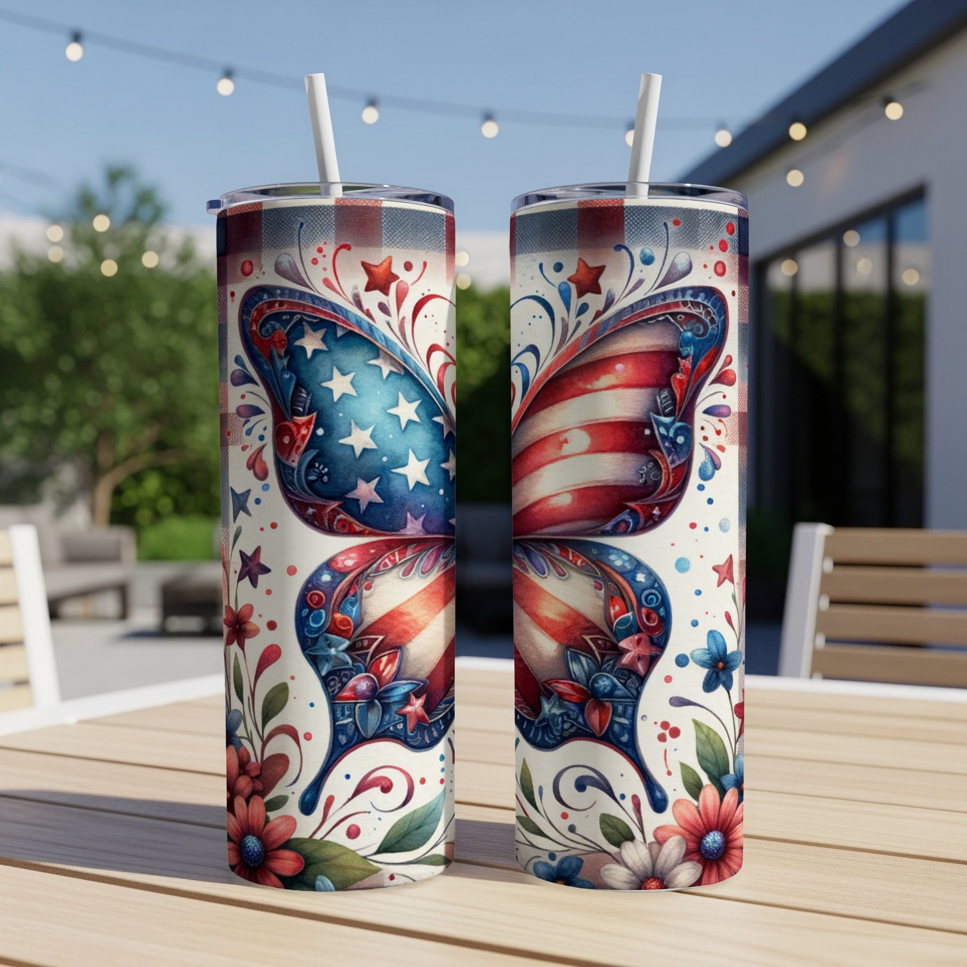 Two patriotic tumblers with butterfly wings and floral designs on a table.