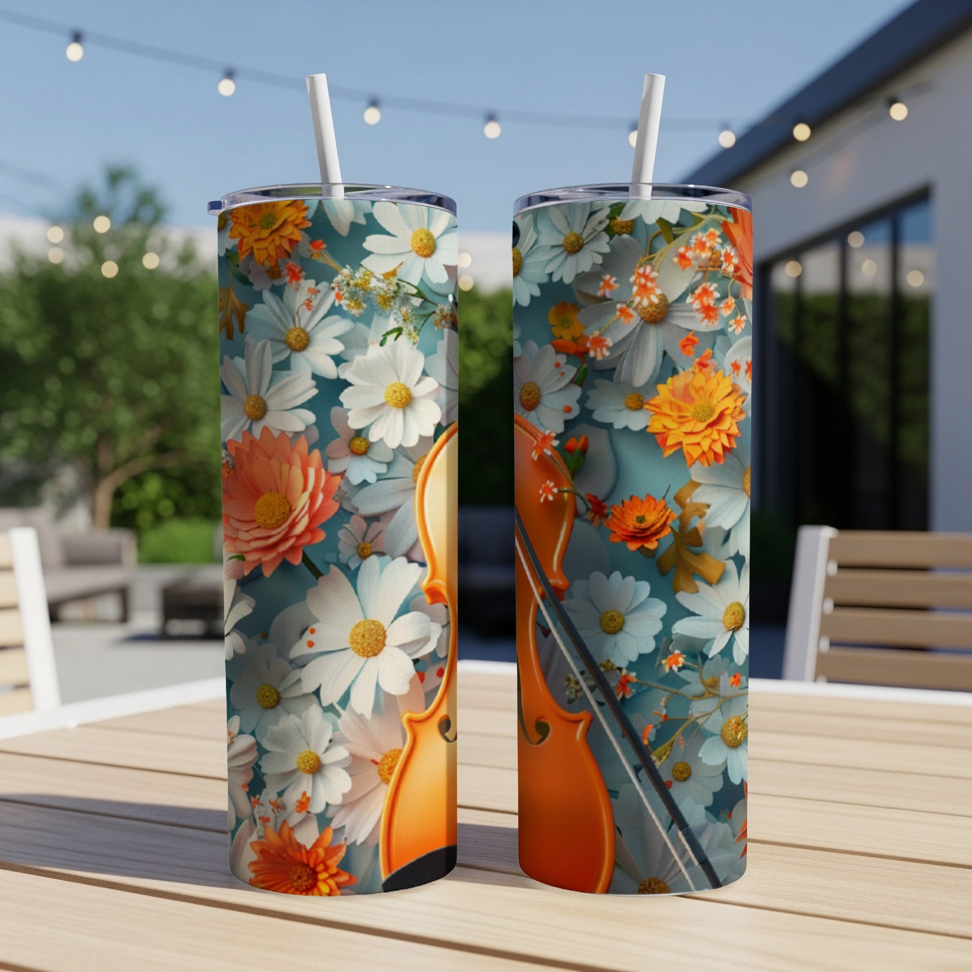 Two tumblers with a floral and violin design on a table outdoors.