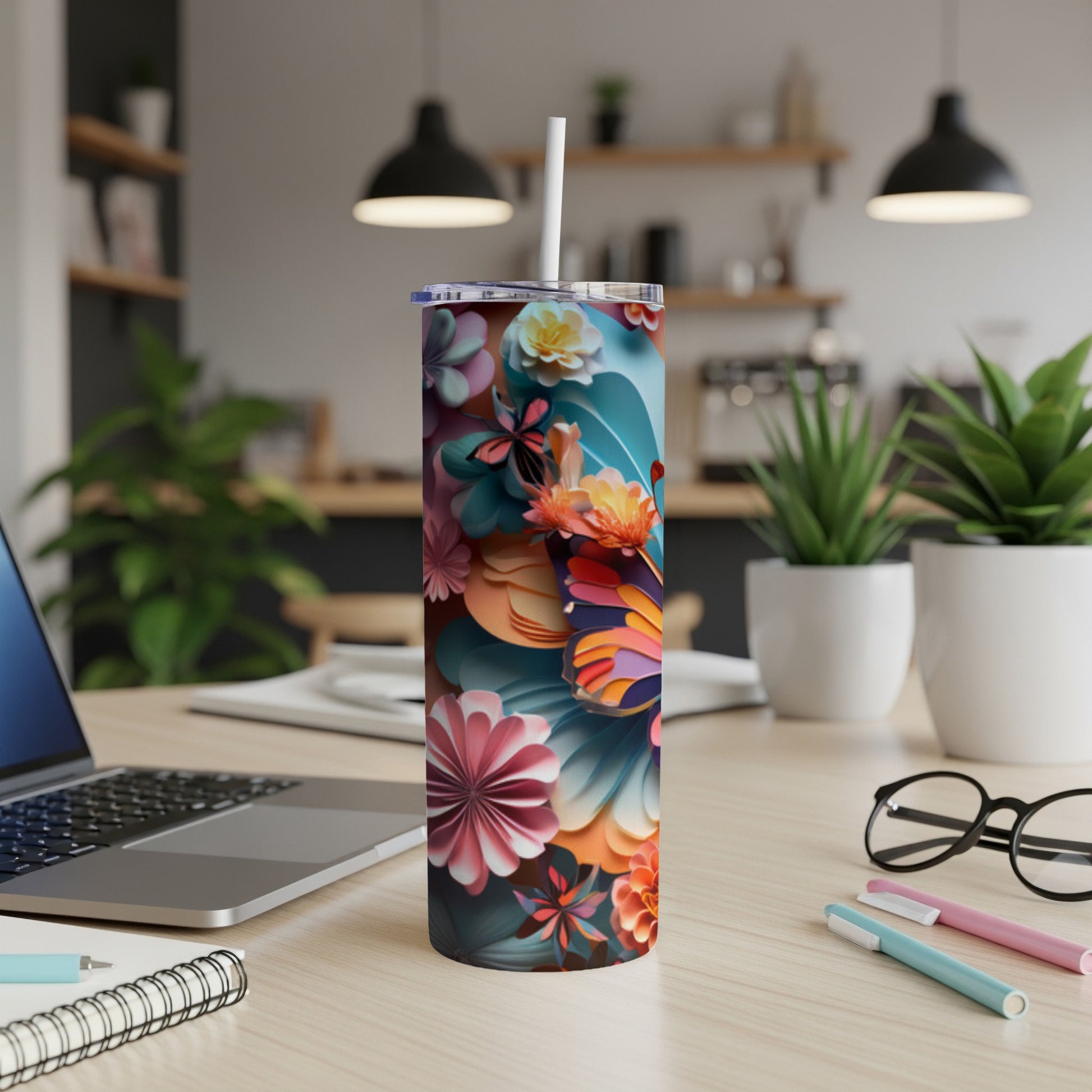 Floral patterned tumbler with straw on a desk.