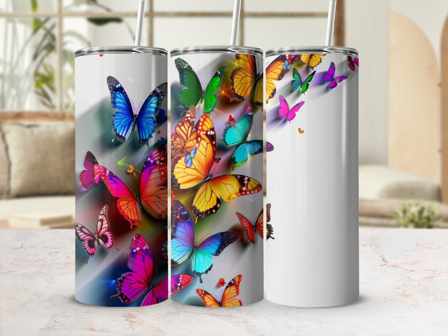 Three tumblers adorned with colorful, vibrant butterflies on a white background.
