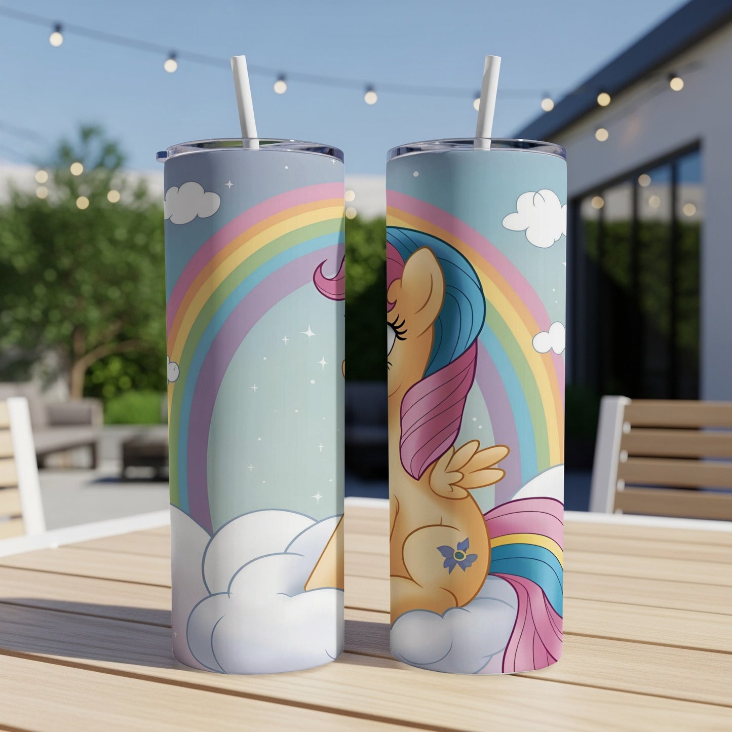 Two colorful tumblers with a winged horse and rainbow on a patio table.