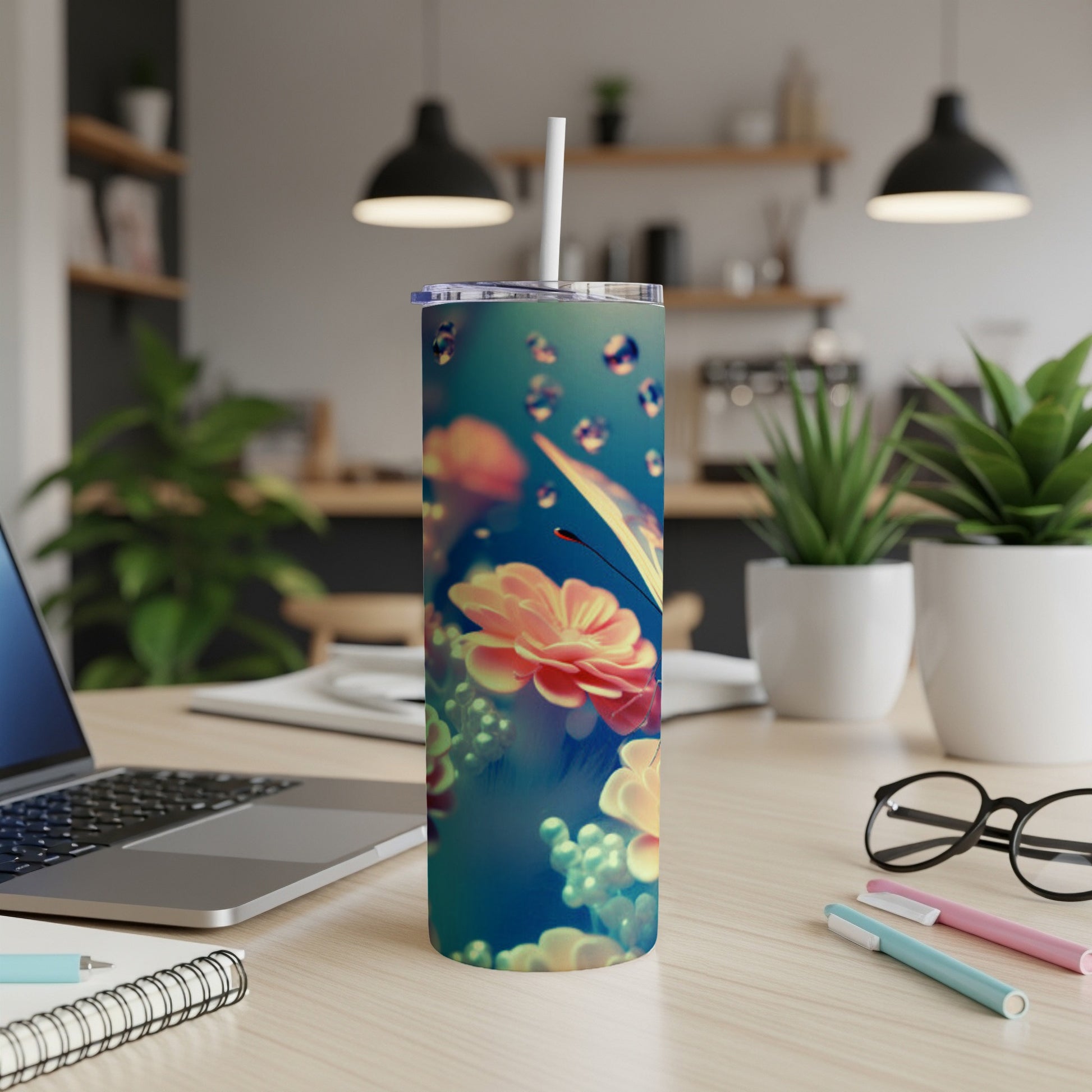 Tumbler with floral and butterfly design, straw, on a desk.