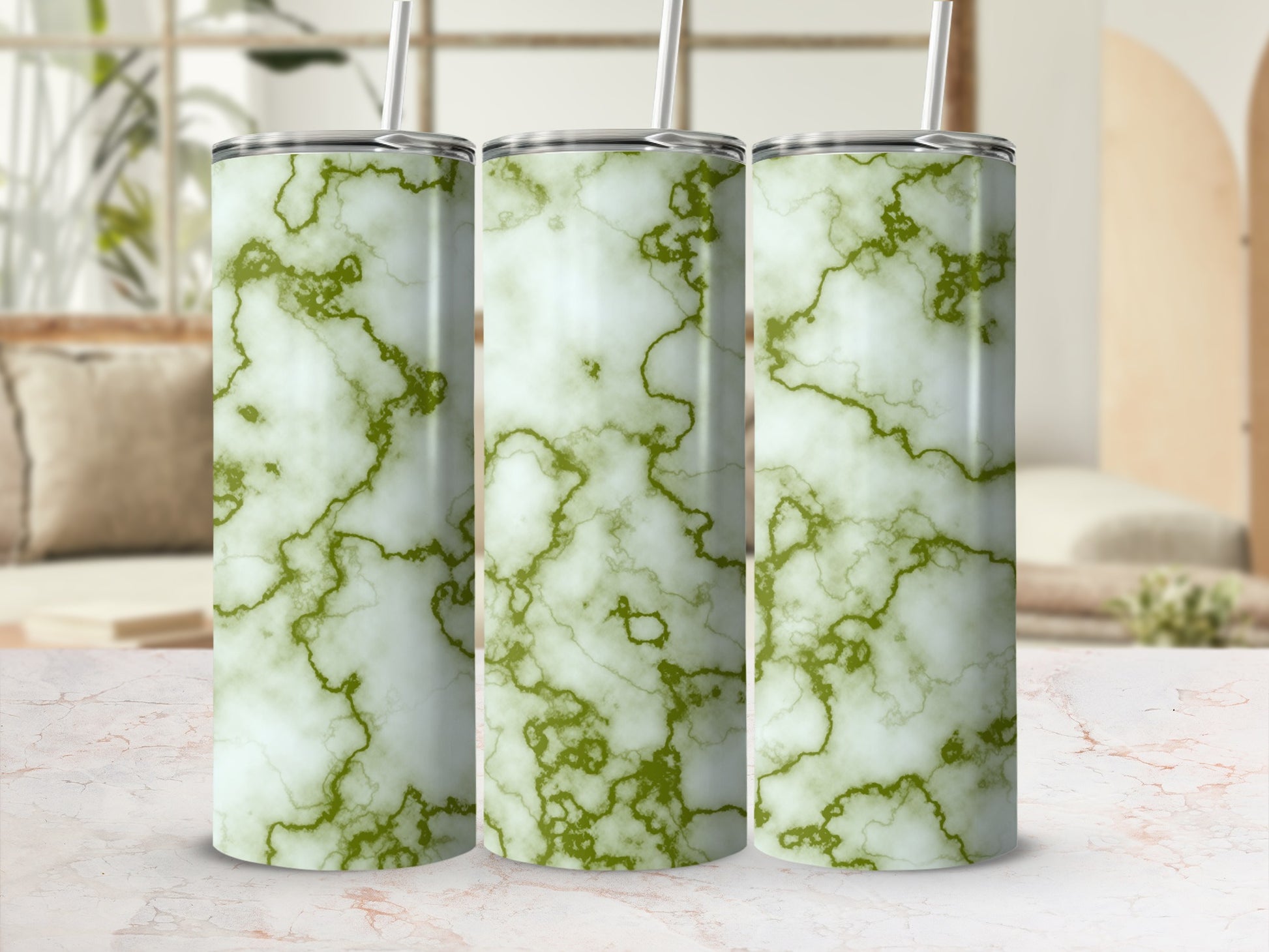 Three green marble pattern tumblers with straws on a counter.