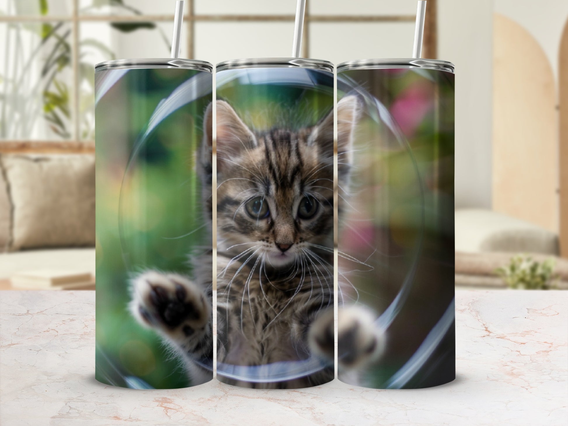 Tabby kitten peering out of a clear tumbler with straw.