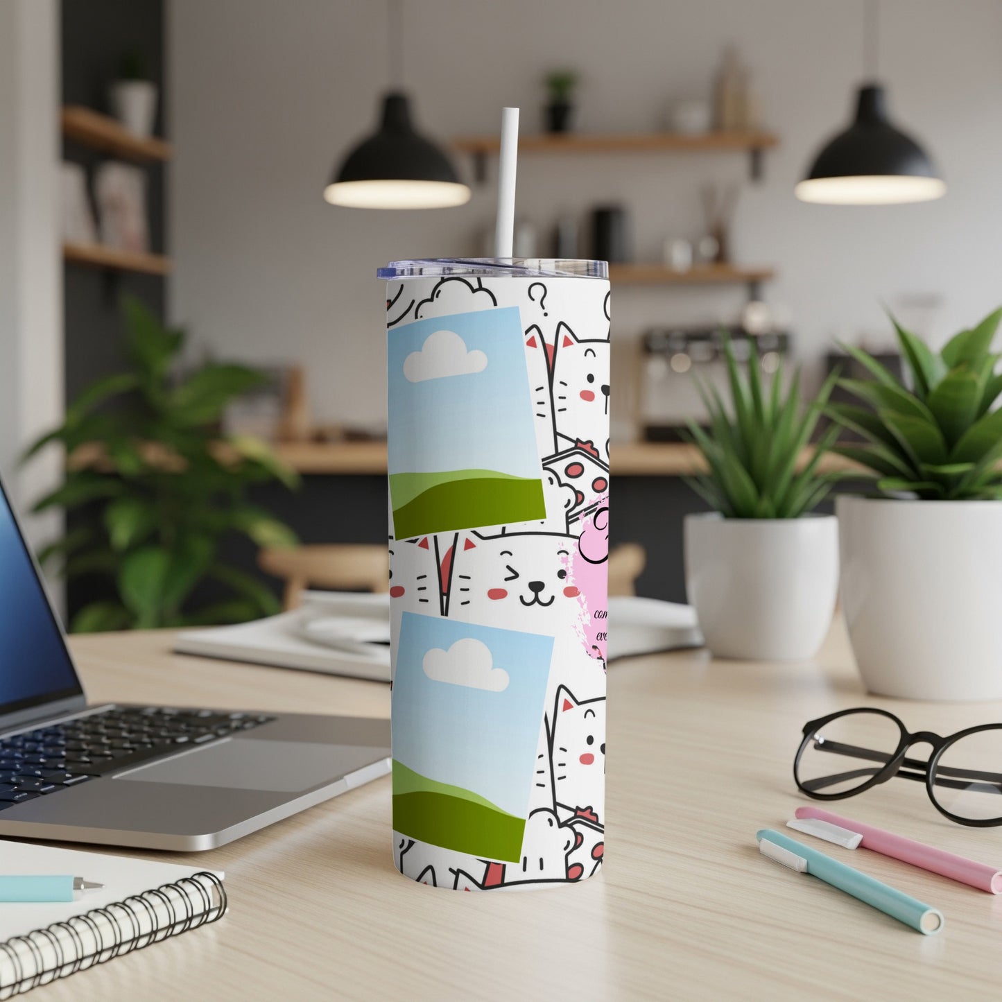 White tumbler with cartoon cats and framed pictures on a desk.