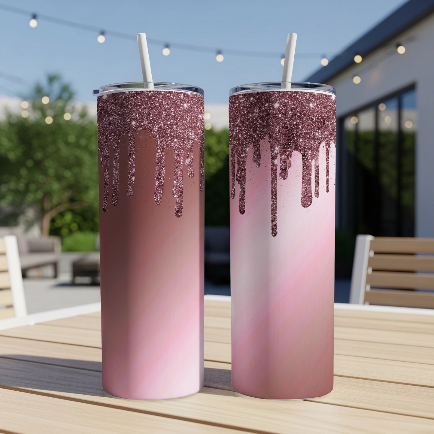 Two rose gold glitter drip tumblers with straws on a wooden table.