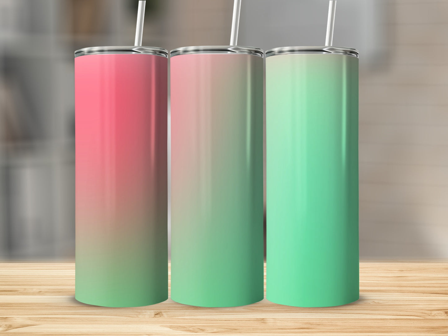 Three gradient colored tumblers with straws on a wooden surface.