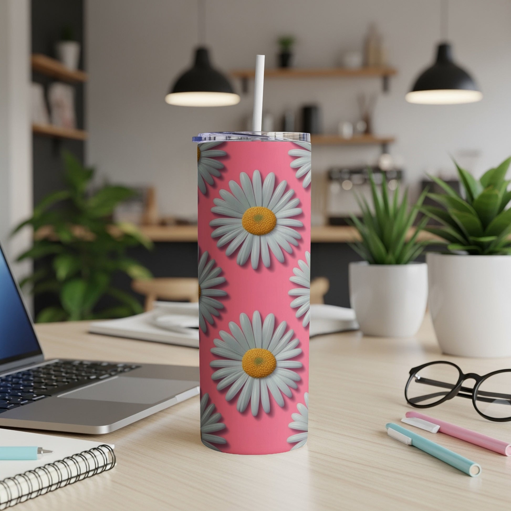 Pink tumbler with white and gray daisies and a white straw.